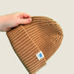 Bronze brown ribbed kids’ beanie with cream 1800m Club label. Made in Arosa, Switzerland.