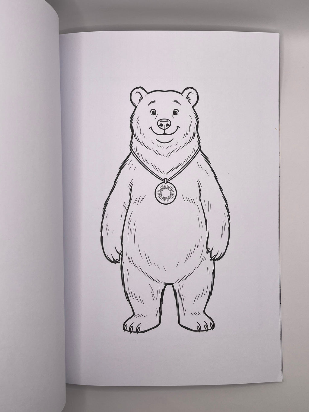 Colouring page with a bear wearing a round pendant