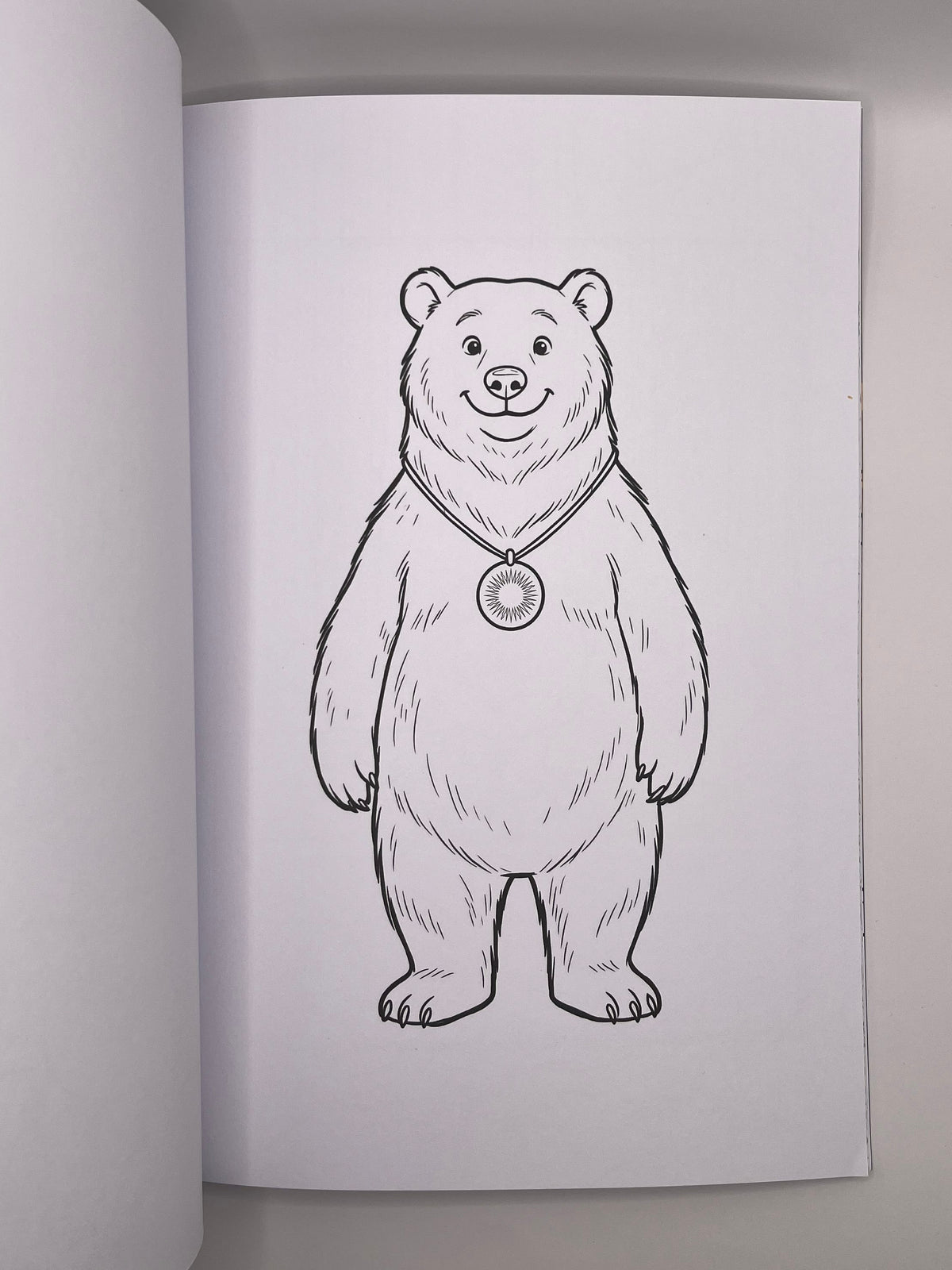 Colouring page with a bear wearing a round pendant