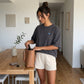 A woman at home wearing the 1800m Club Hörnli embroidered Boxy T-shirt designed in Arosa, Switzerland.