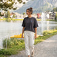 A woman walking along the Arosa Obersee wearing the 1800m Club Hörnli embroidered Boxy T-shirt designed in Arosa, Switzerland.