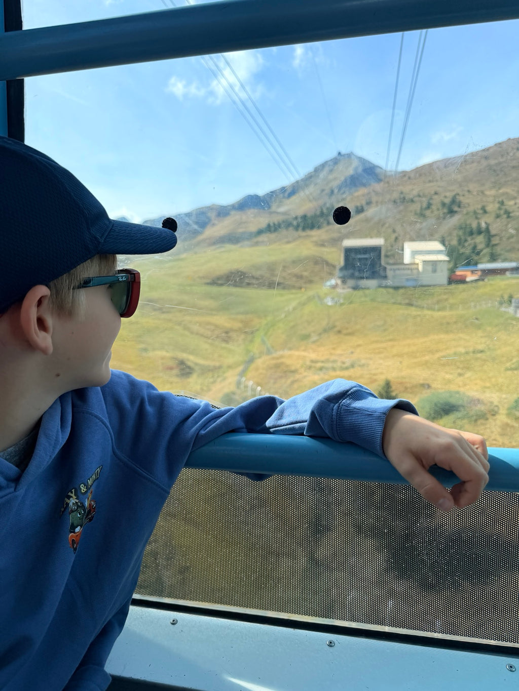 The blue Ray & Monty Road Trip kids' hoodie worn on a cable-car ride in the mountains.
